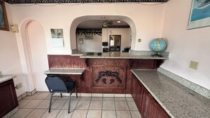 A kitchen with a marble countertop, a wooden cabinet with a decorative handle, a chair, and a globe on the counter.