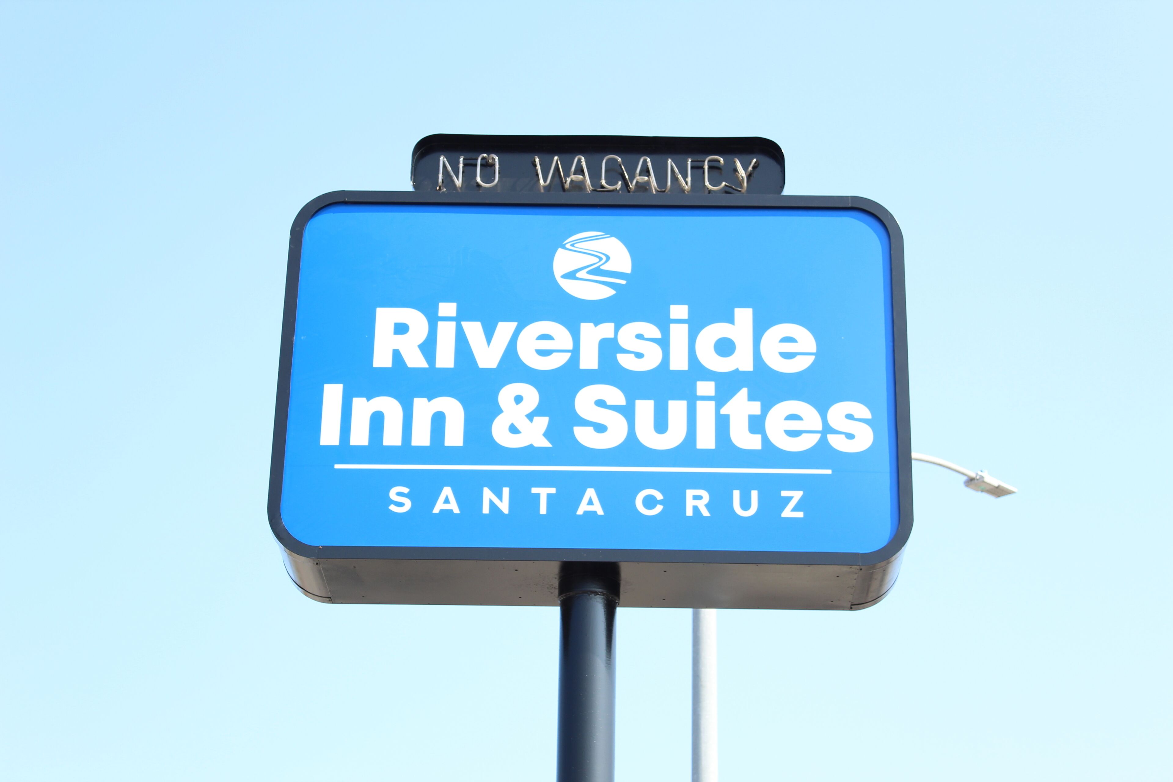 A sign for Riverside Inn & Suites in Santa Cruz with a 'NO VACANCY' notice.