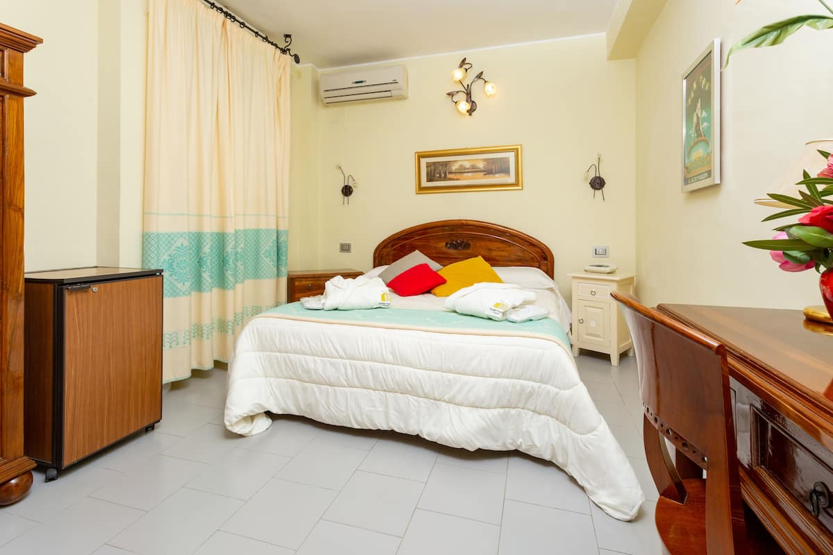 Un dormitorio ordenado con cama, mesitas de noche, armario y aire acondicionado.