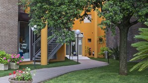 A building with a brick facade, a yellow exterior, and a staircase leading to an entrance. - Hotel Marini (Sassari)