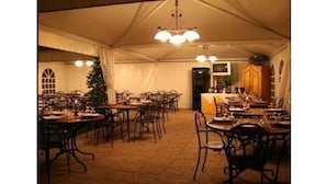A tented dining area with multiple tables and chairs, a Christmas tree, and a bar area. - Hotel Marini (Sassari)