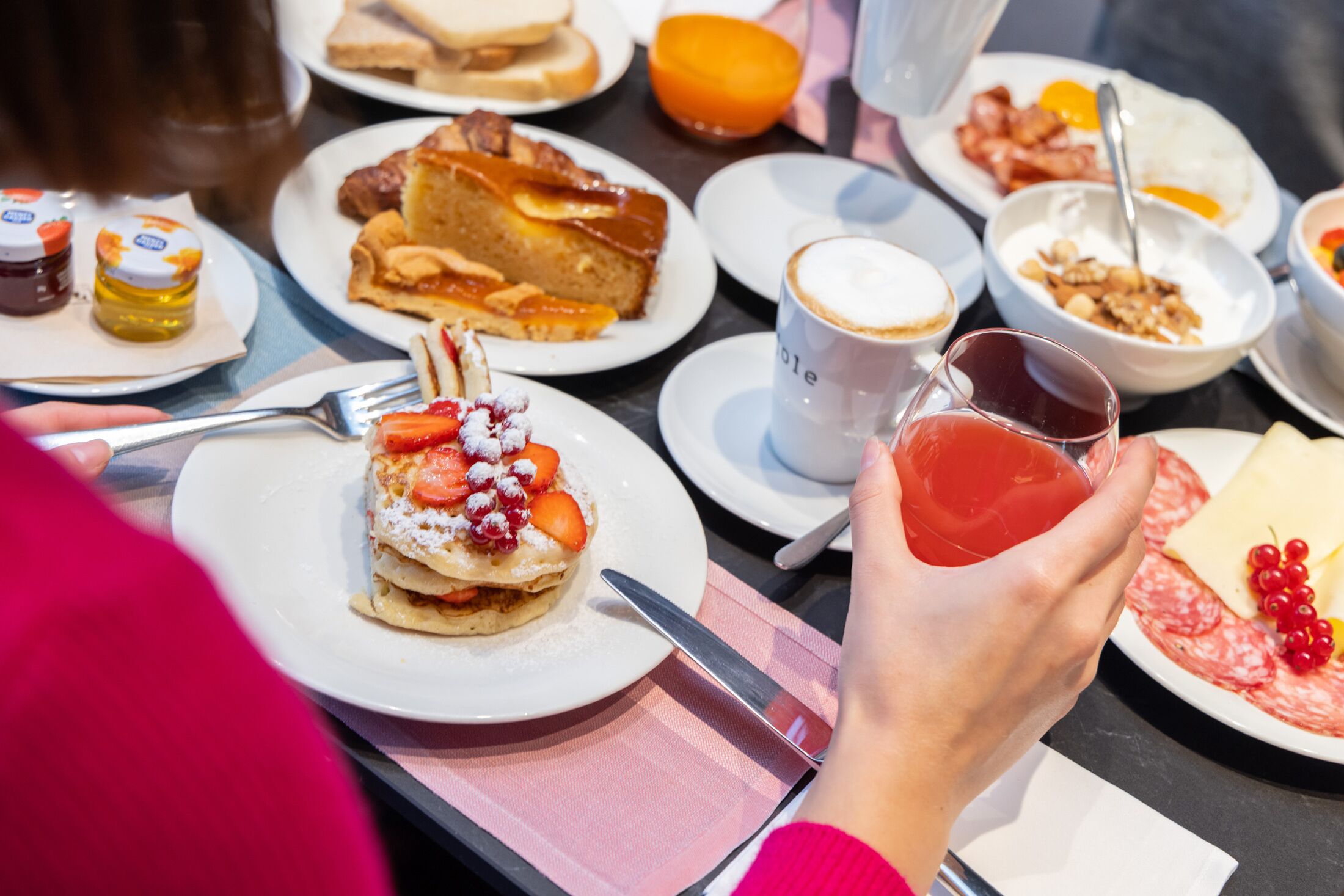 A breakfast setting with various dishes including pastries, fruits, and beverages.