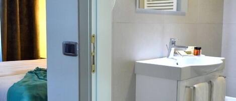 A hotel bathroom with a sink, mirror, and towel rack.