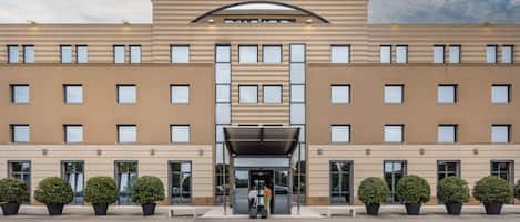 A modern hotel with a prominent "OMNIAHOTEL" sign, a central entrance with a canopy, and symmetrical windows.