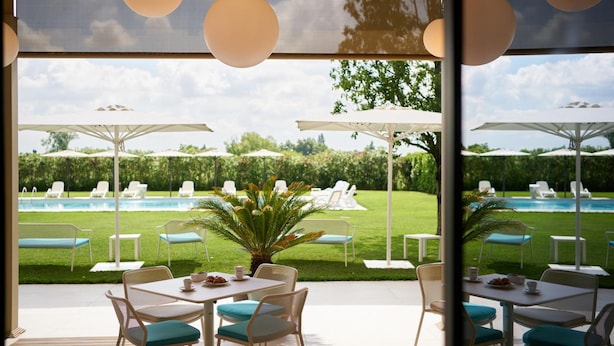 An outdoor patio with tables and chairs, a pool, and umbrellas.