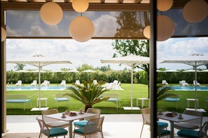An outdoor patio with tables and chairs, a pool, and umbrellas. - Hotel Omnia (Noventa di Piave)