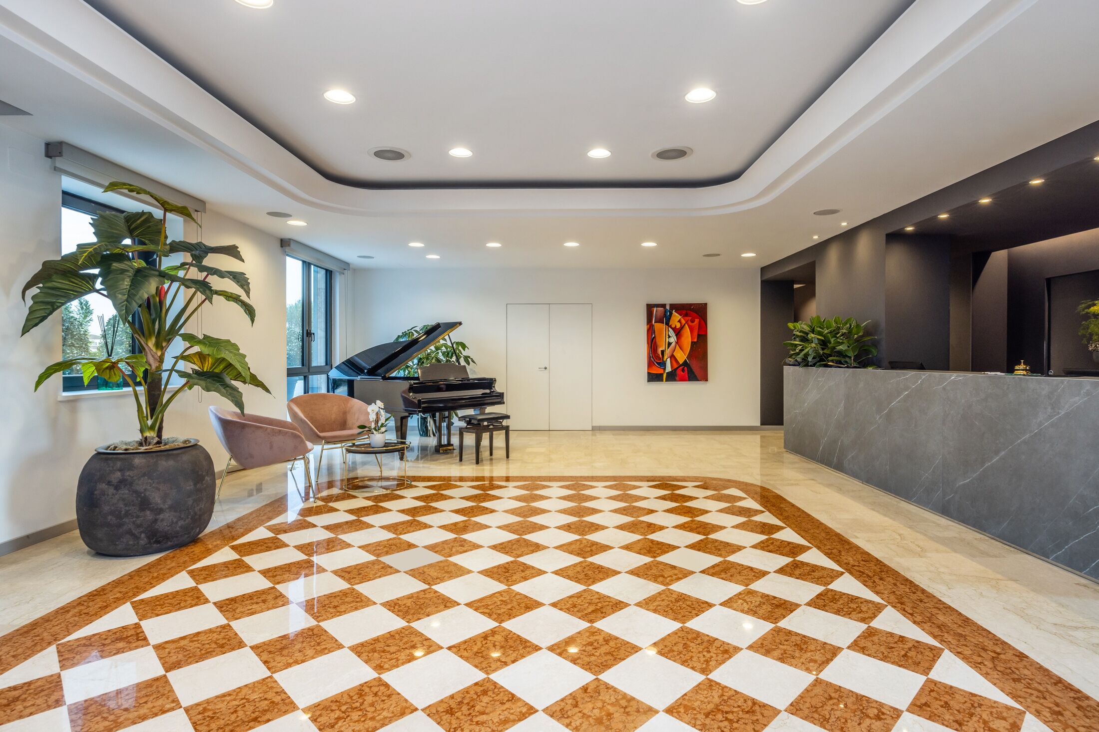 A lobby with a checkered floor, a grand piano, a reception desk, and potted plants.