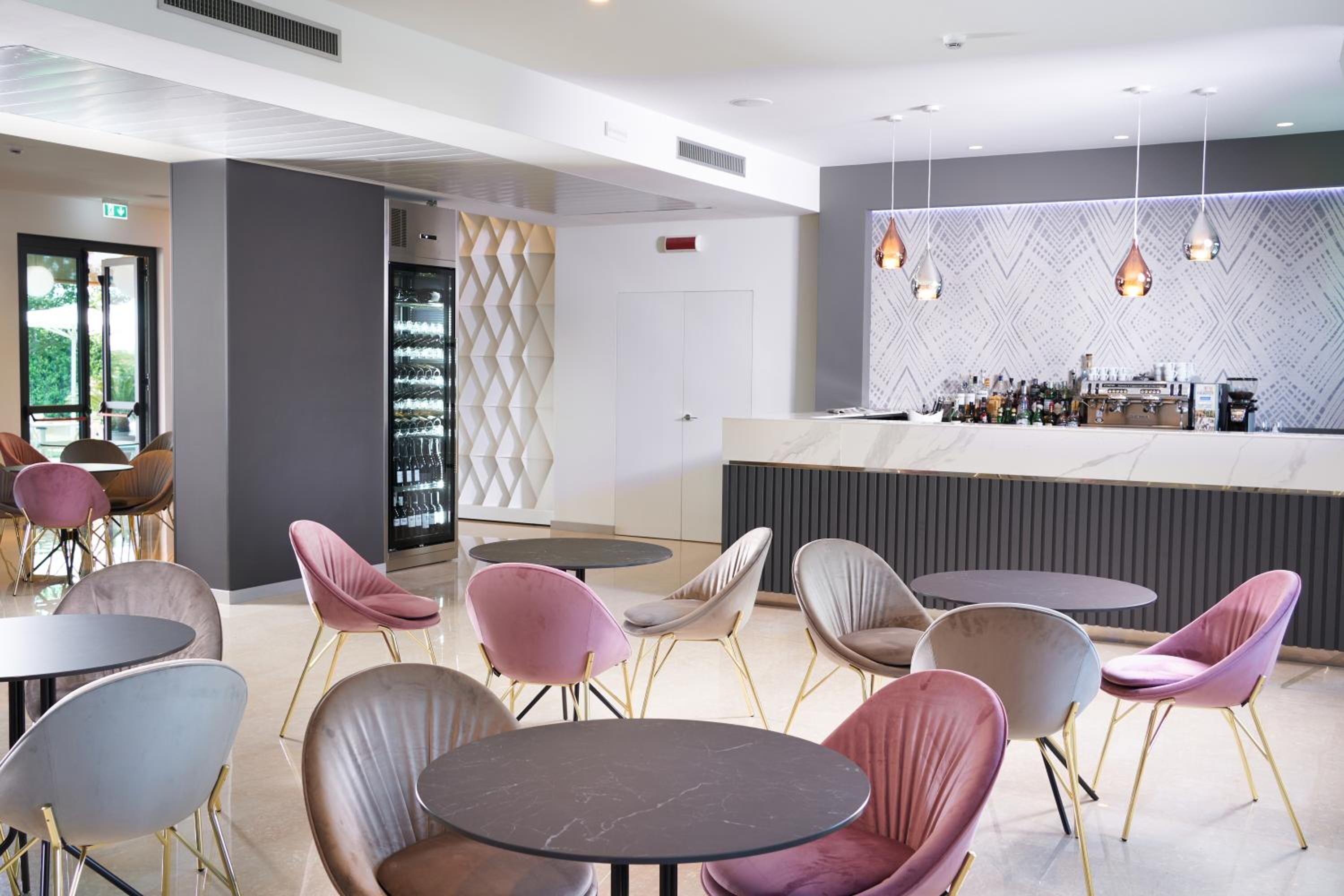 A modern bar area with round tables and chairs, a wine rack, and a patterned wall.