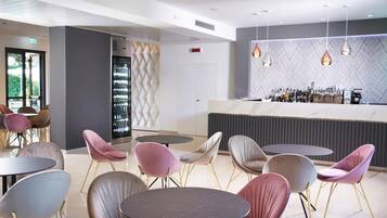 A modern bar area with round tables and chairs, a wine rack, and a patterned wall.