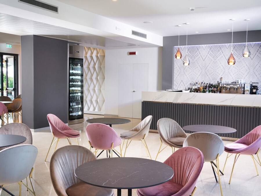 A modern bar area with round tables and chairs, a wine rack, and a patterned wall.
