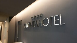 A reception desk with a sign that reads "OMINTAHOTEL" and three stars above it.