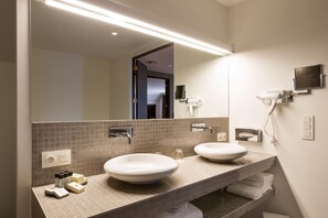 Un baño moderno con dos lavamanos, un espejo grande y un secador de pelo montado en la pared.
