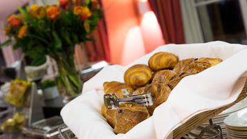 A basket of croissants and a vase of flowers on a buffet table.