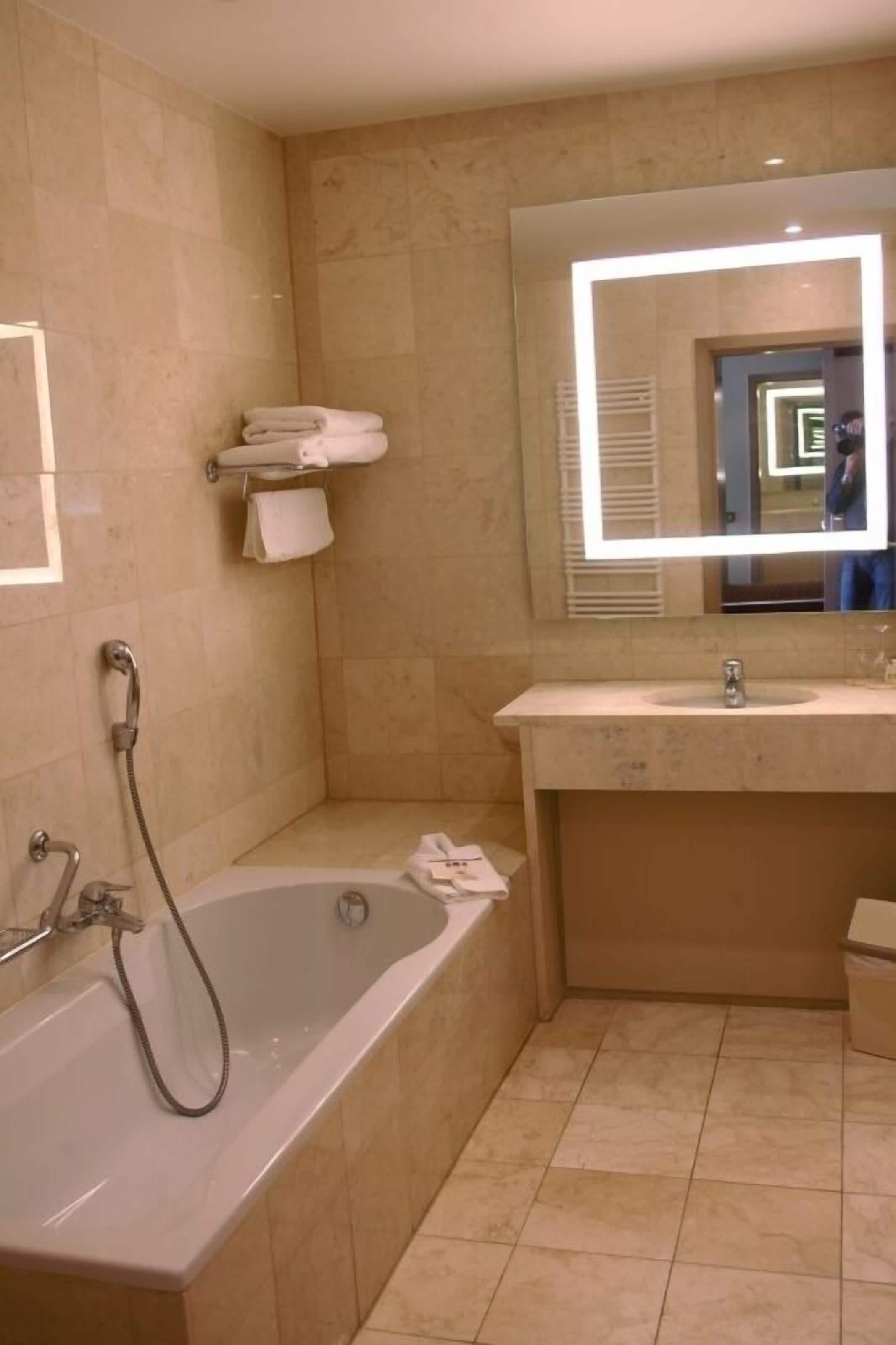 A bathroom with a bathtub, a sink, a mirror, and a towel rack.
