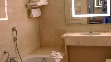 A bathroom with a bathtub, a sink, a mirror, and a towel rack.