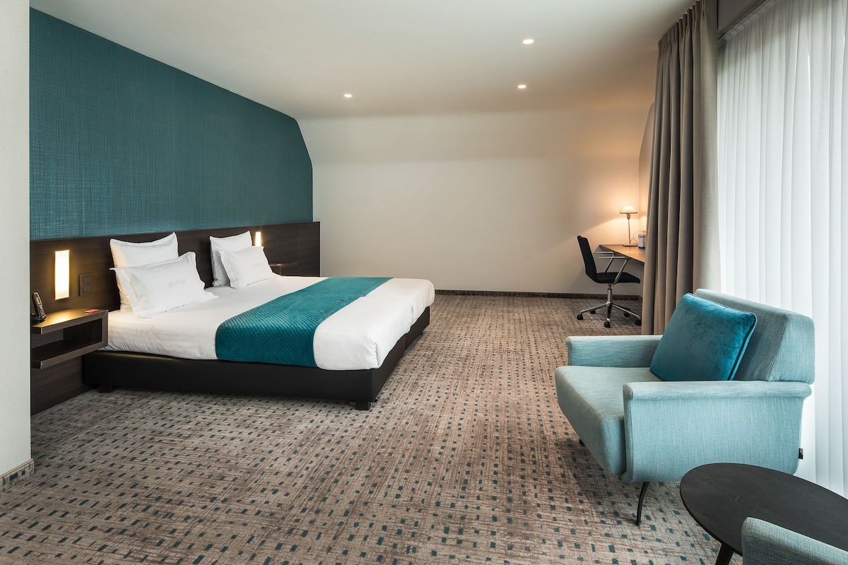 Una habitación de hotel con una cama grande, un escritorio, una silla y una mesita.