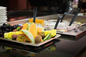 Un bufé con diversas frutas y una selección de bebidas.