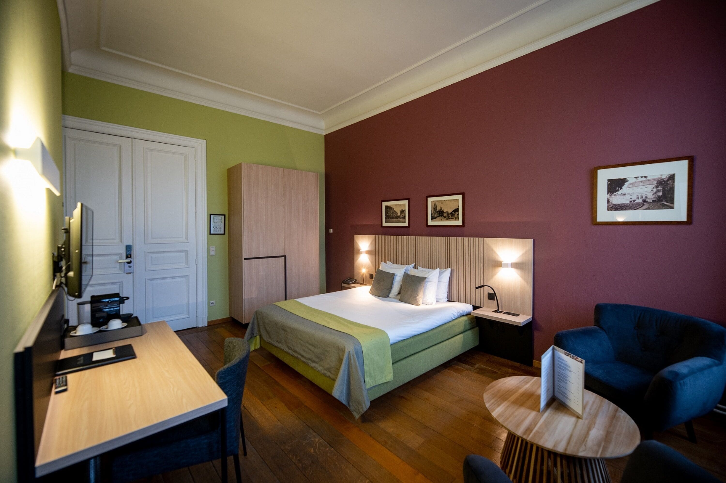 Una habitación de hotel con cama, escritorio, silla, mesita y armario.