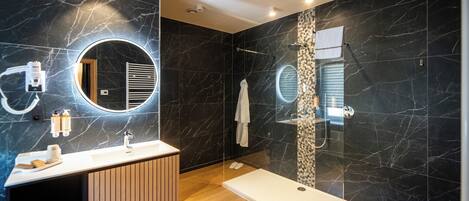 Un baño moderno con tocador, espejo y zona de ducha.