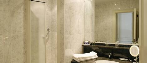 A modern bathroom with a glass shower enclosure, a black countertop sink, and a large mirror.