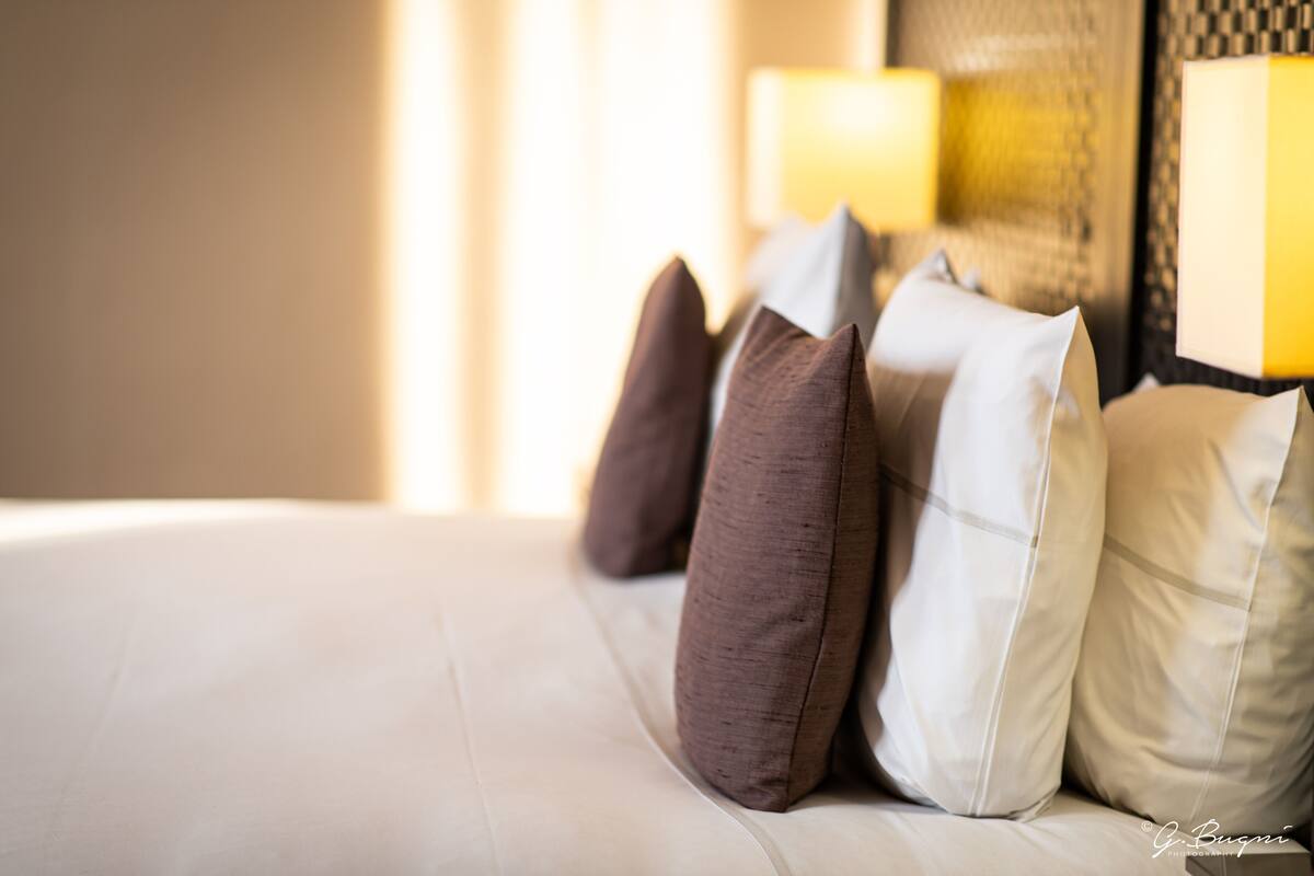 A neatly made bed with several pillows in shades of brown and white.