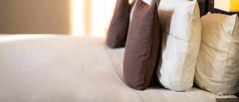 A neatly made bed with several pillows in shades of brown and white.