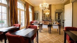 A dining area with wooden flooring, red upholstered chairs, and a chandelier.
