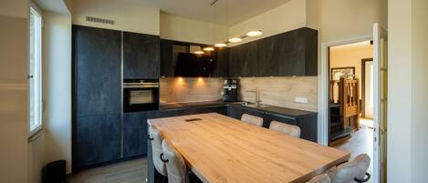 Una cocina moderna con armarios oscuros, una mesa de comedor de madera e iluminación empotrada.