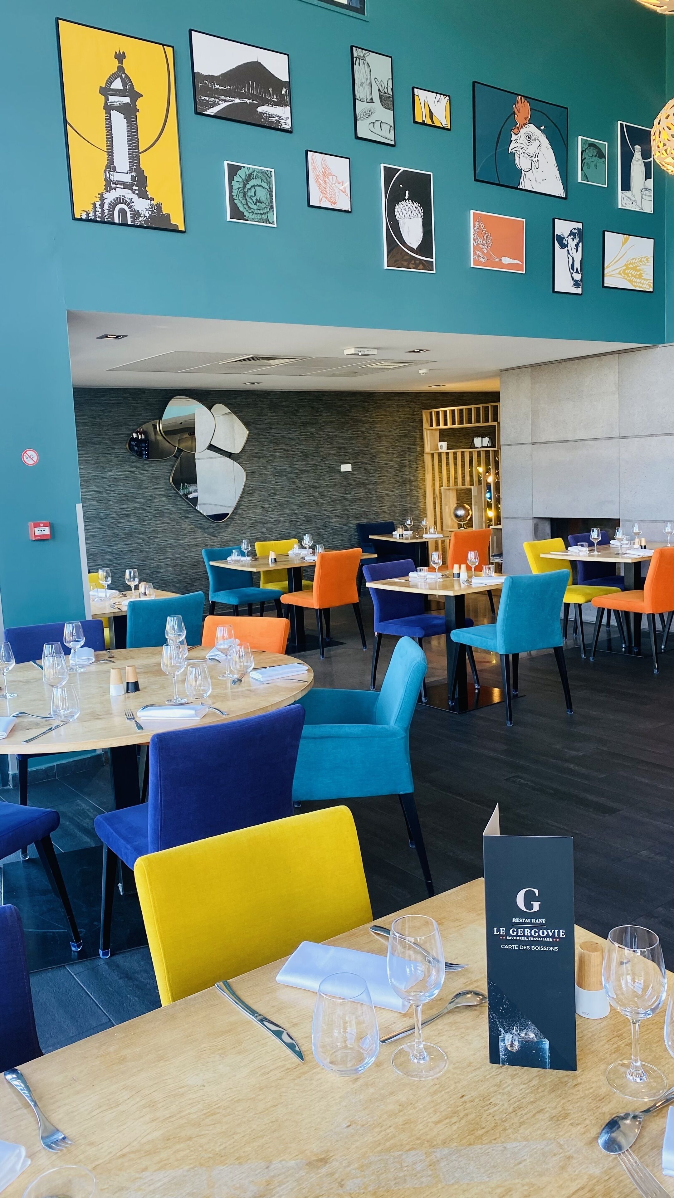 A restaurant interior with colorful chairs and tables, artwork on the walls, and a menu stand.