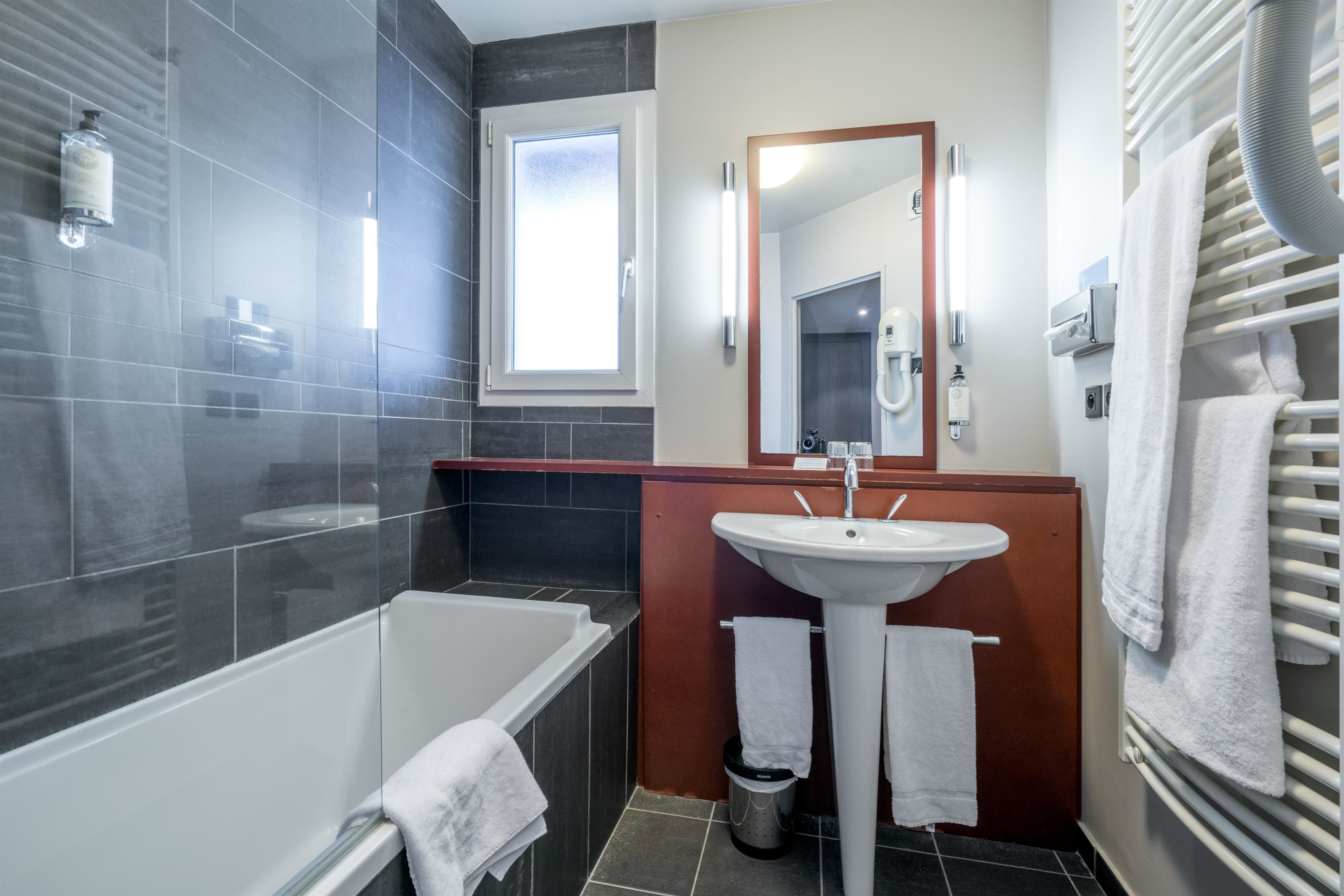 Un baño moderno con bañera, lavamanos y espejo.