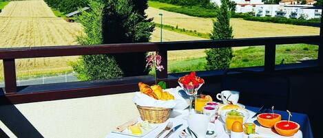 A table set for breakfast with a view of a rural landscape.