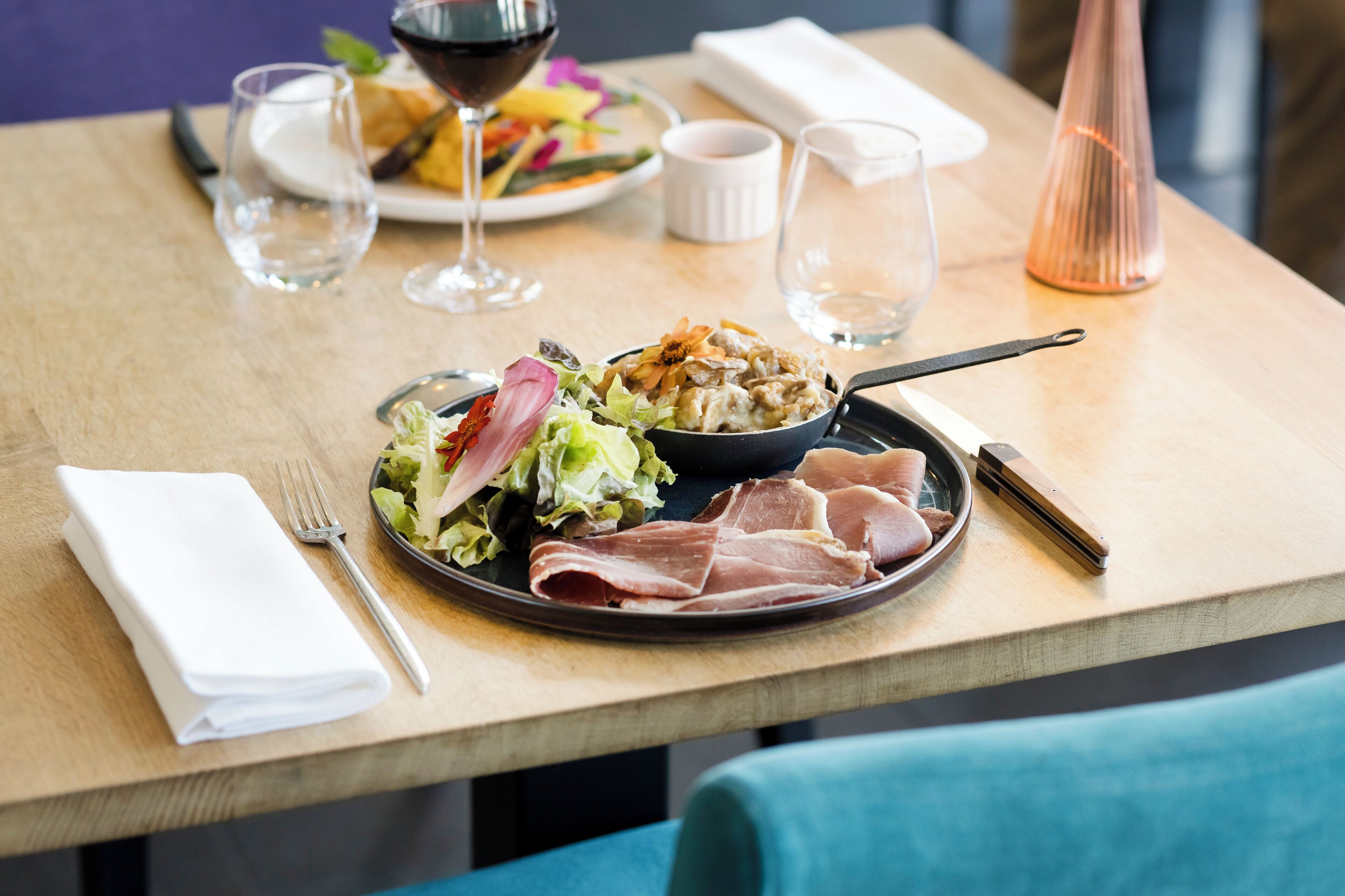Una mesa de comedor con un plato de comida, una copa de vino y una vela.