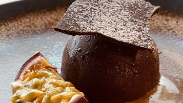 Un dessert composé d’une demi-sphère de chocolat noir et d’une sauce au caramel, le tout présenté sur une assiette.
