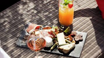 Ett bord av rotting med en bricka med charkuterier och ett glas vin.
