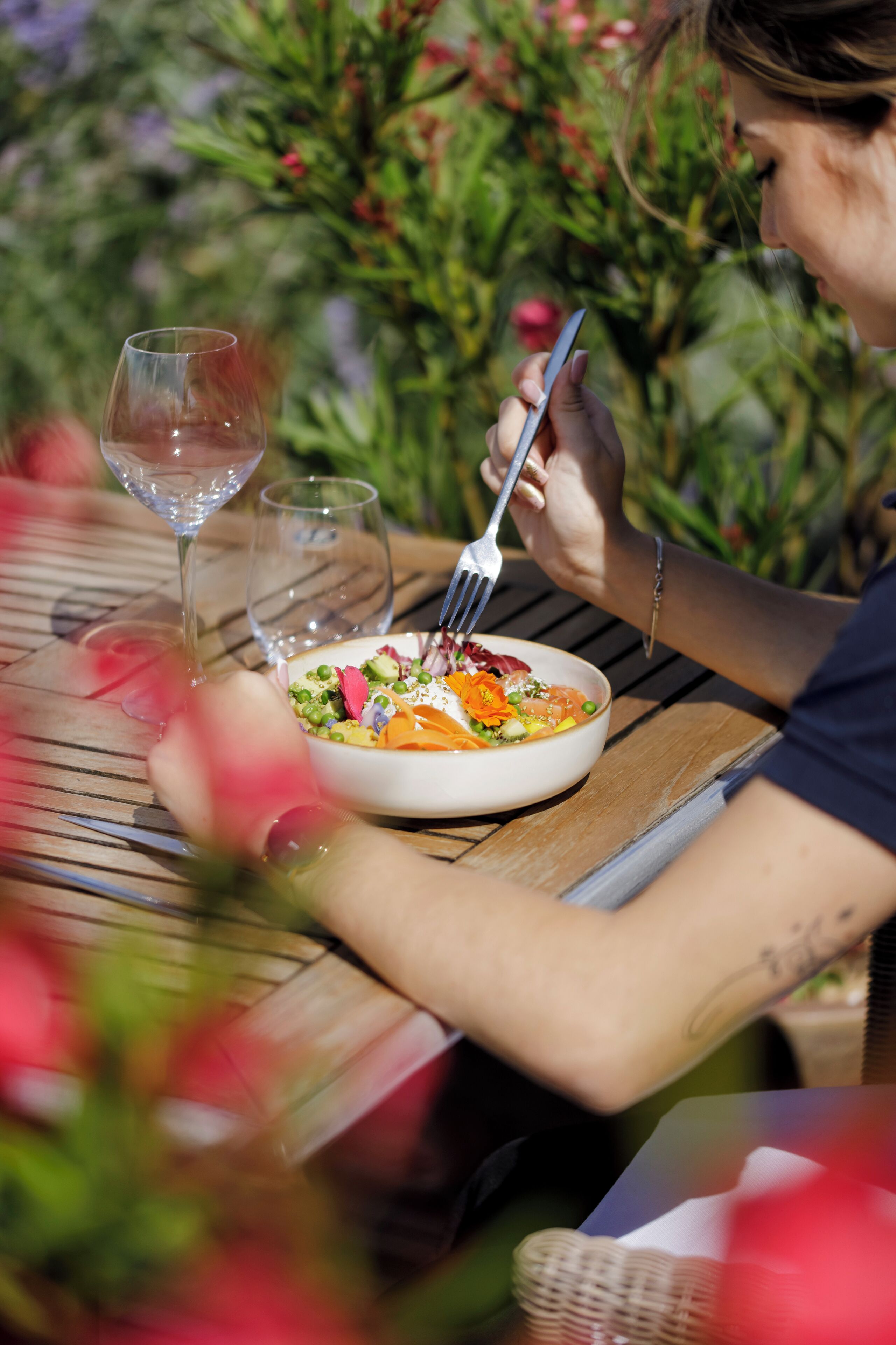 Une table à manger avec un saladier rempli de salade et un verre à vin.