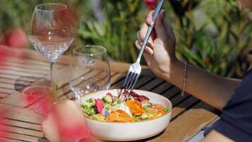 Une table à manger avec un saladier rempli de salade et un verre à vin.
