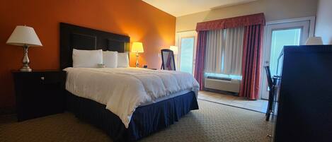 Une chambre d’hôtel avec un grand lit, deux tables de chevet avec des lampes, une fenêtre avec des rideaux et un appareil de climatisation.