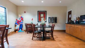 A dining area with a large table and chairs, a decorative wall piece, and a kitchen area with cabinets and appliances.