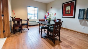 A dining area with wooden flooring, a table with chairs, a window, and decorative items on the walls. - Grand Hotel  (Spring City)