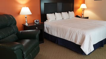 Une chambre d’hôtel avec un lit, un fauteuil en cuir vert, deux tables de chevet avec des lampes et une horloge posée sur l’une des tables.