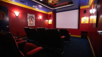 Une salle de cinéma avec des sièges rouges, un grand écran et des appliques murales.