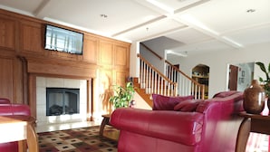 A living room with a fireplace, a red leather sofa, a wooden coffee table, and a staircase leading to another level. - Grand Hotel  (Spring City)