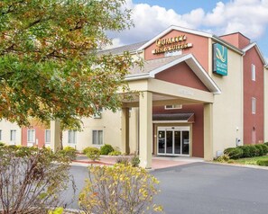 Un hotel con un cartel que dice 'Quality Inn & Suites' y un letrero que indica 'Clearance 12'6' sobre la entrada.