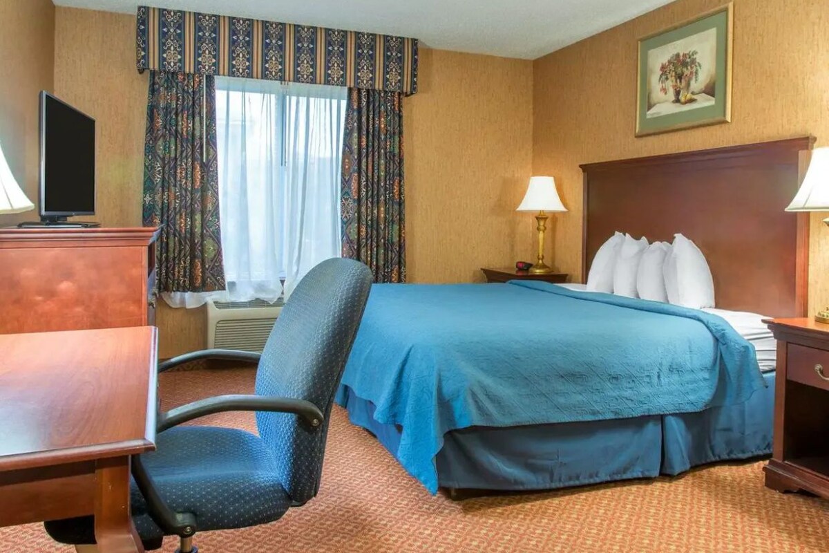 Une chambre d’hôtel équipée d’un lit, d’un bureau, d’une chaise et d’un téléviseur.