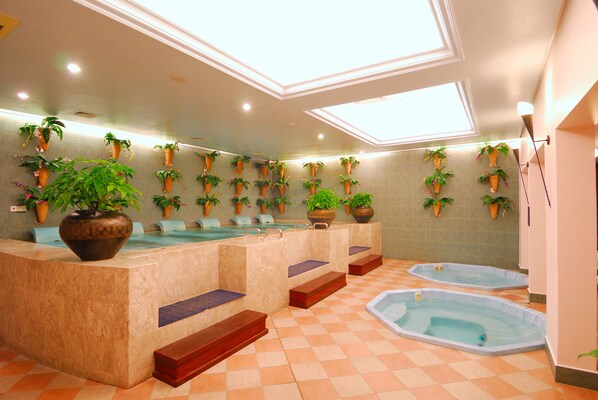 Een wellnessruimte met verschillende jacuzzi’s en plantenpotten.