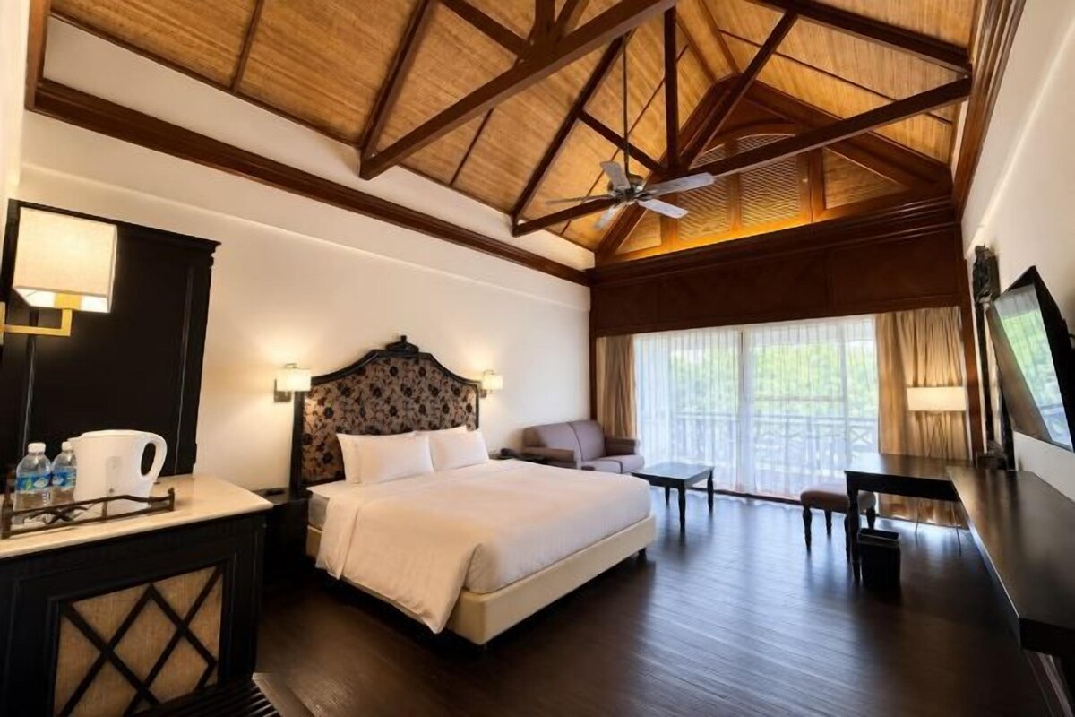 Een hotelkamer met een bed, bureau, stoel en een groot raam.