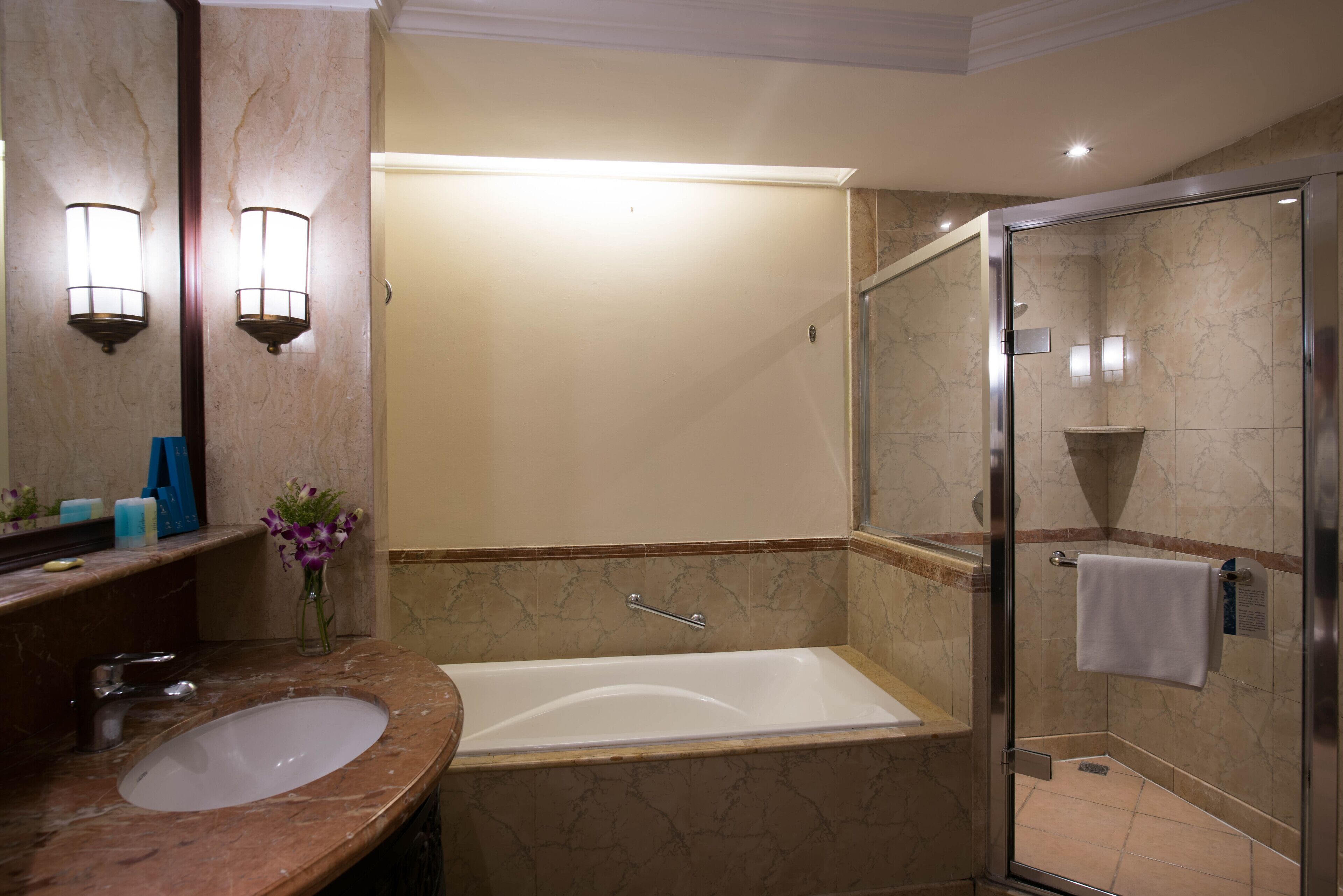 A bathroom with a marble sink, a bathtub, and a glass-enclosed shower.