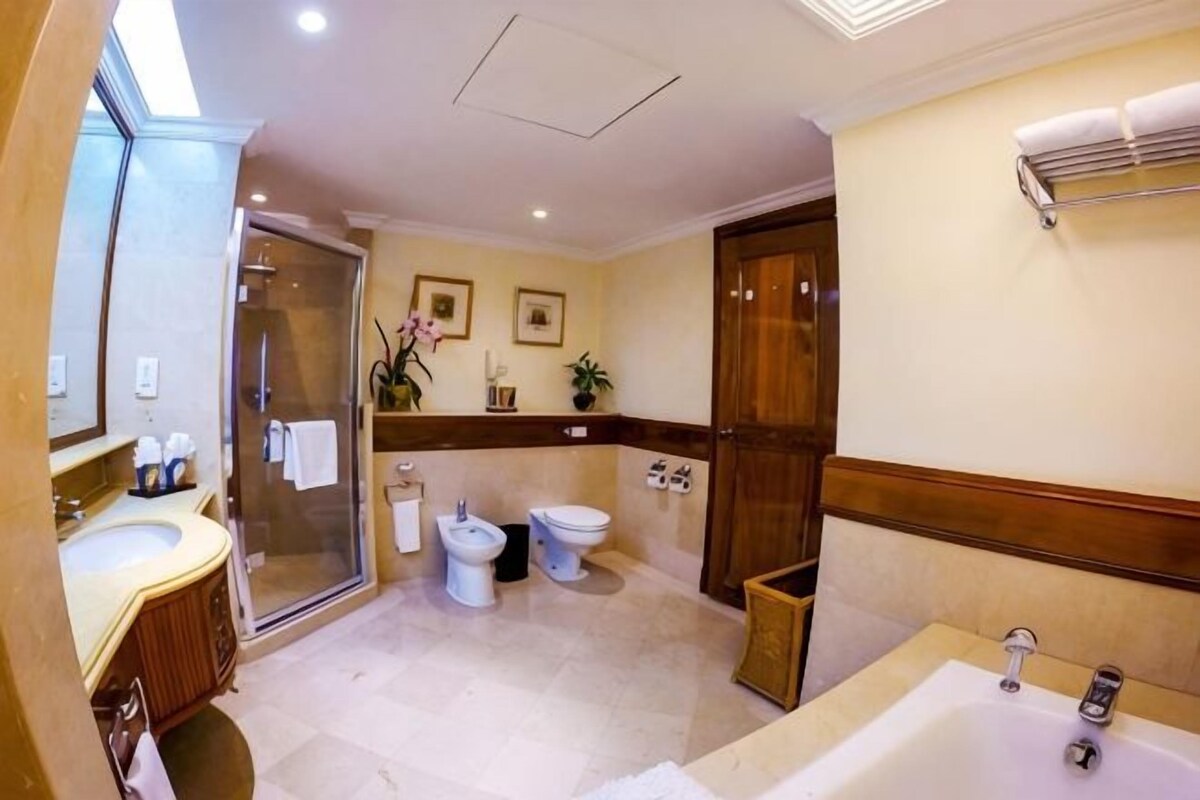 Een badkamer met een bad, een douche en twee toiletten.