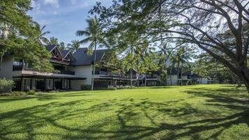 A large, open grassy area with a building featuring multiple balconies and a sloped roof.