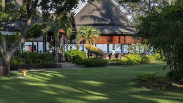 A resort with a thatched-roof structure, surrounded by lush greenery and a well-maintained lawn.